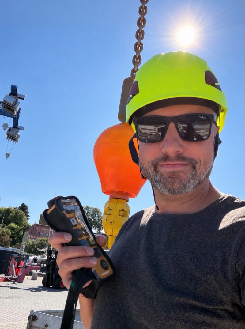 Anders in a hard hat operating a harbour crane with a remote control
