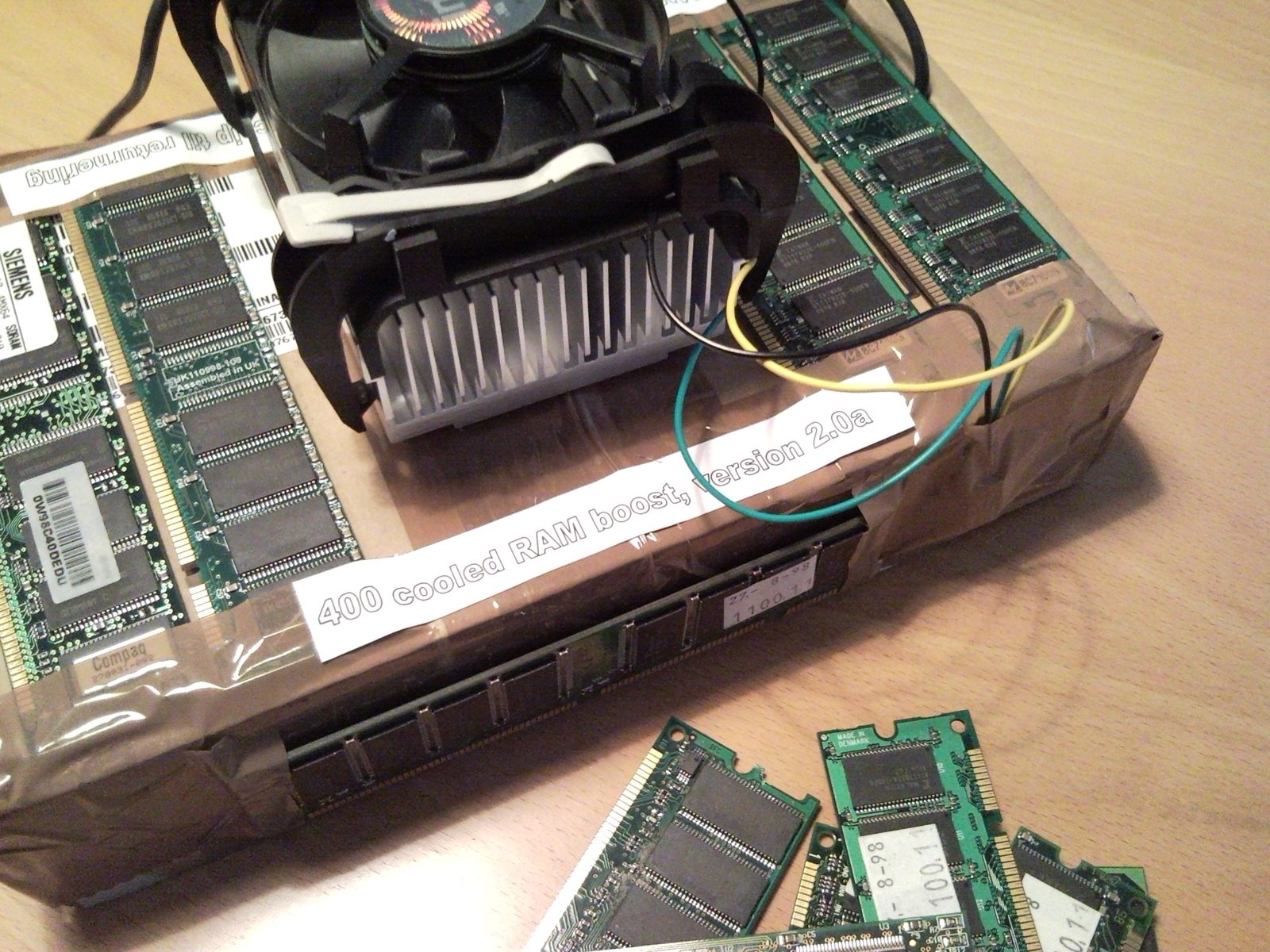 A cardboard box wrapped in tape and covered in RAM modules, with a CPU cooler on top and a label reading '400 cooled RAM boost, version 2.0a'